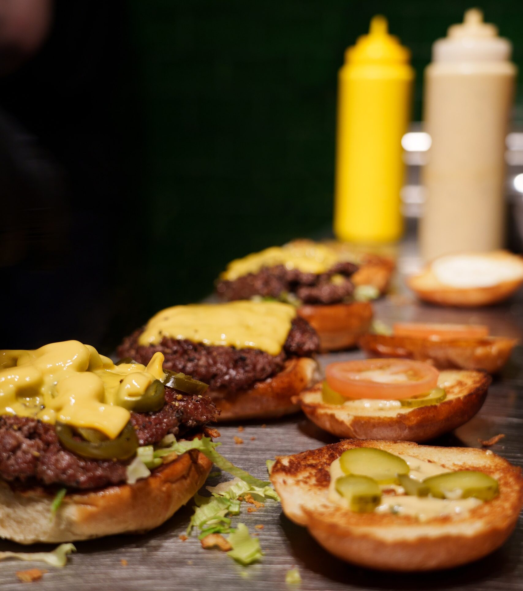 Offene Hamburgerbrötchen mit Patties, Käse und Belägen an der Port Island Hamburg-Theke. Port Island Hamburg