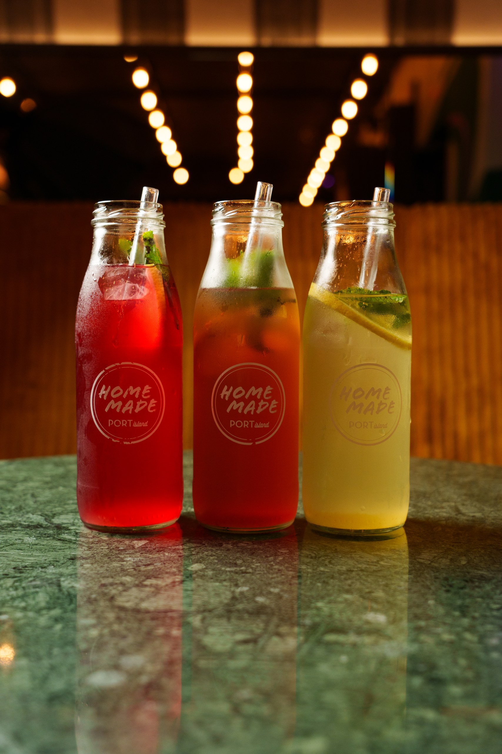 Bunte hausgemachte Getränke in Glasflaschen im Port Island Hamburg, grüner Marmortisch. Port Island Hamburg