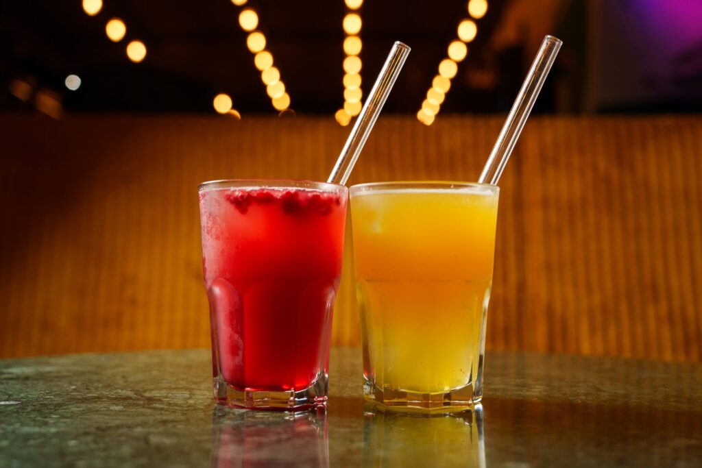 Bunte Cocktails mit Granatapfel auf der Hafeninsel Hamburg, leuchtende Lichter im Hintergrund. Port Island Hamburg