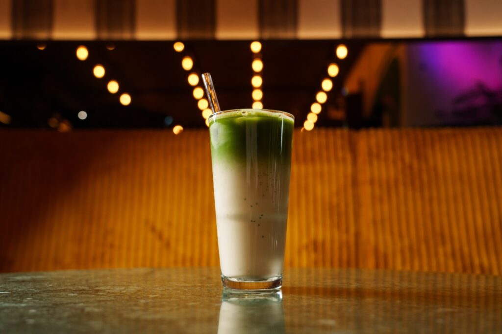 Geeister Matcha Latte mit Milch im Port Island Hamburg, grün-weiße Schichten, gemütliches Licht. Port Island Hamburg